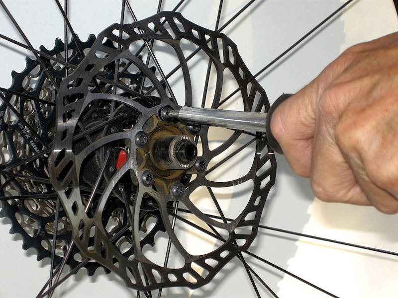 Remove the wheel and unscrew the offending brake rotor. Place the screws in a clean dry place. They have thread-locking material applied to the threads so they need to remain grease and oil free.