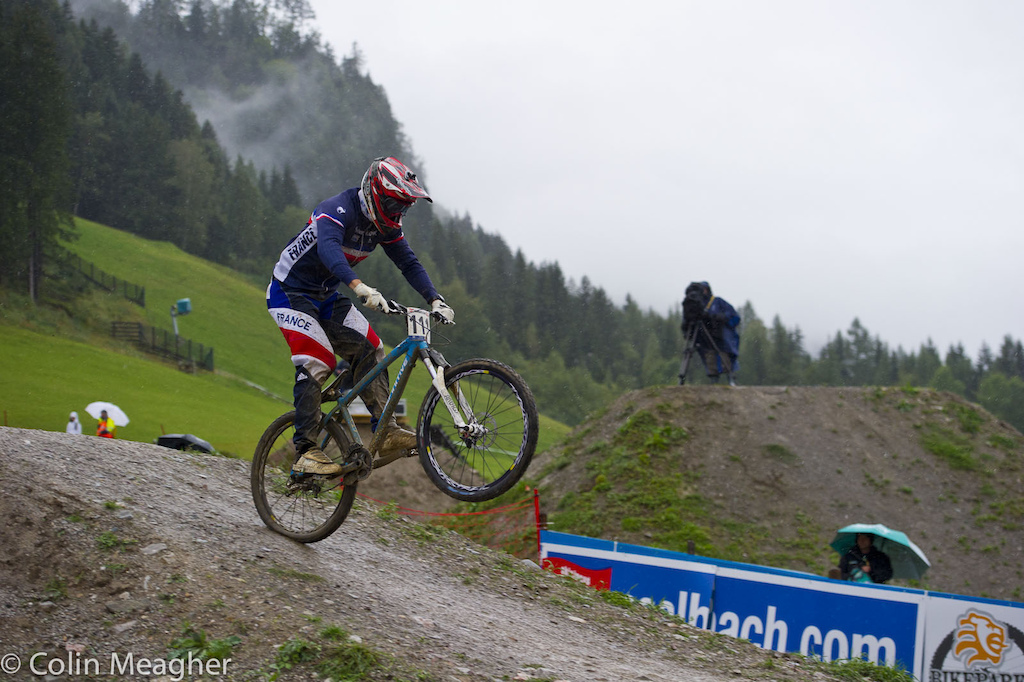 Rider 111 Sylvain Andre checking tire pressure on the bottom section of track.